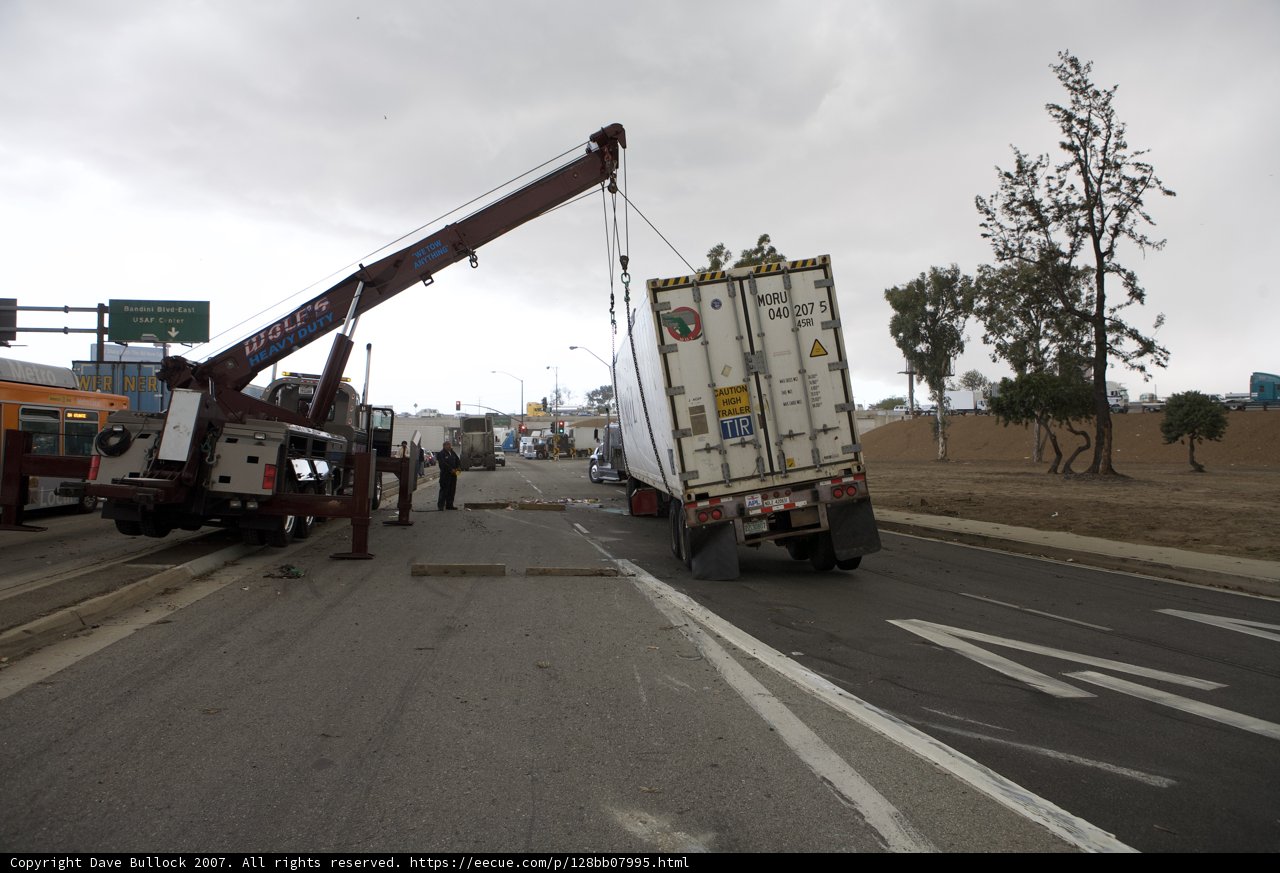 Crane lifting overturned truck off street