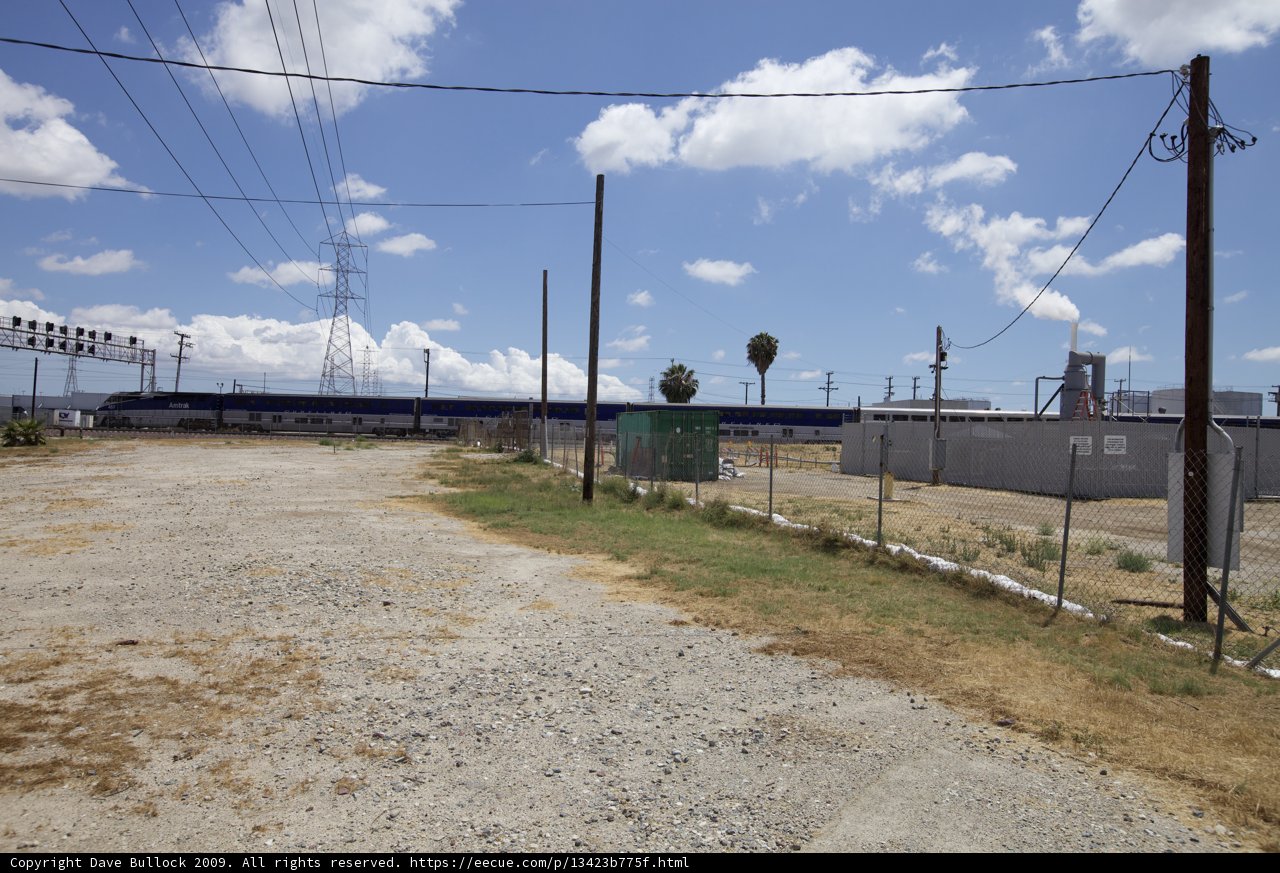 A Gravel Road with Power Lines and Fence