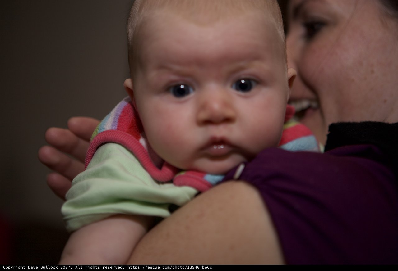 Curious Baby Gazes Forward Over Parent's Shoulder