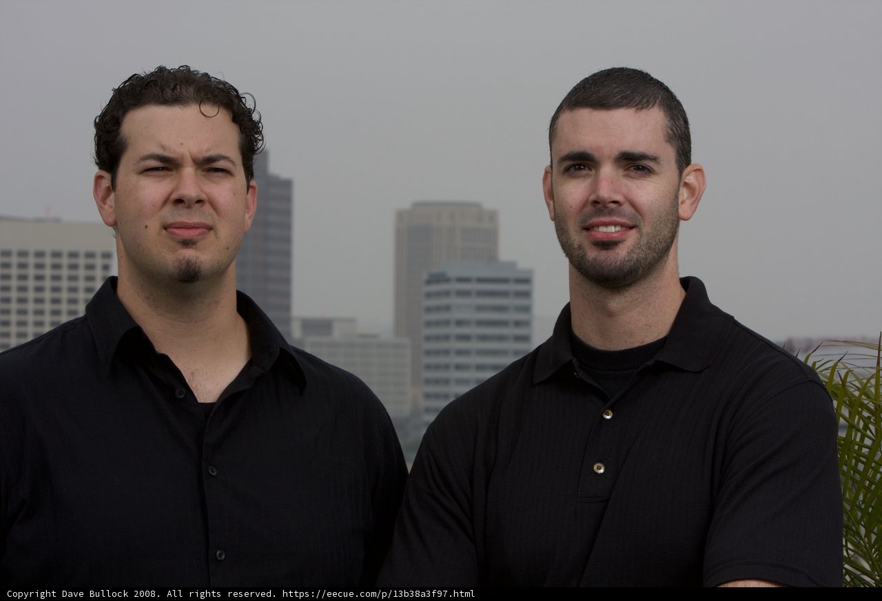 Two Happy Men in Black Shirts by Skyscraper