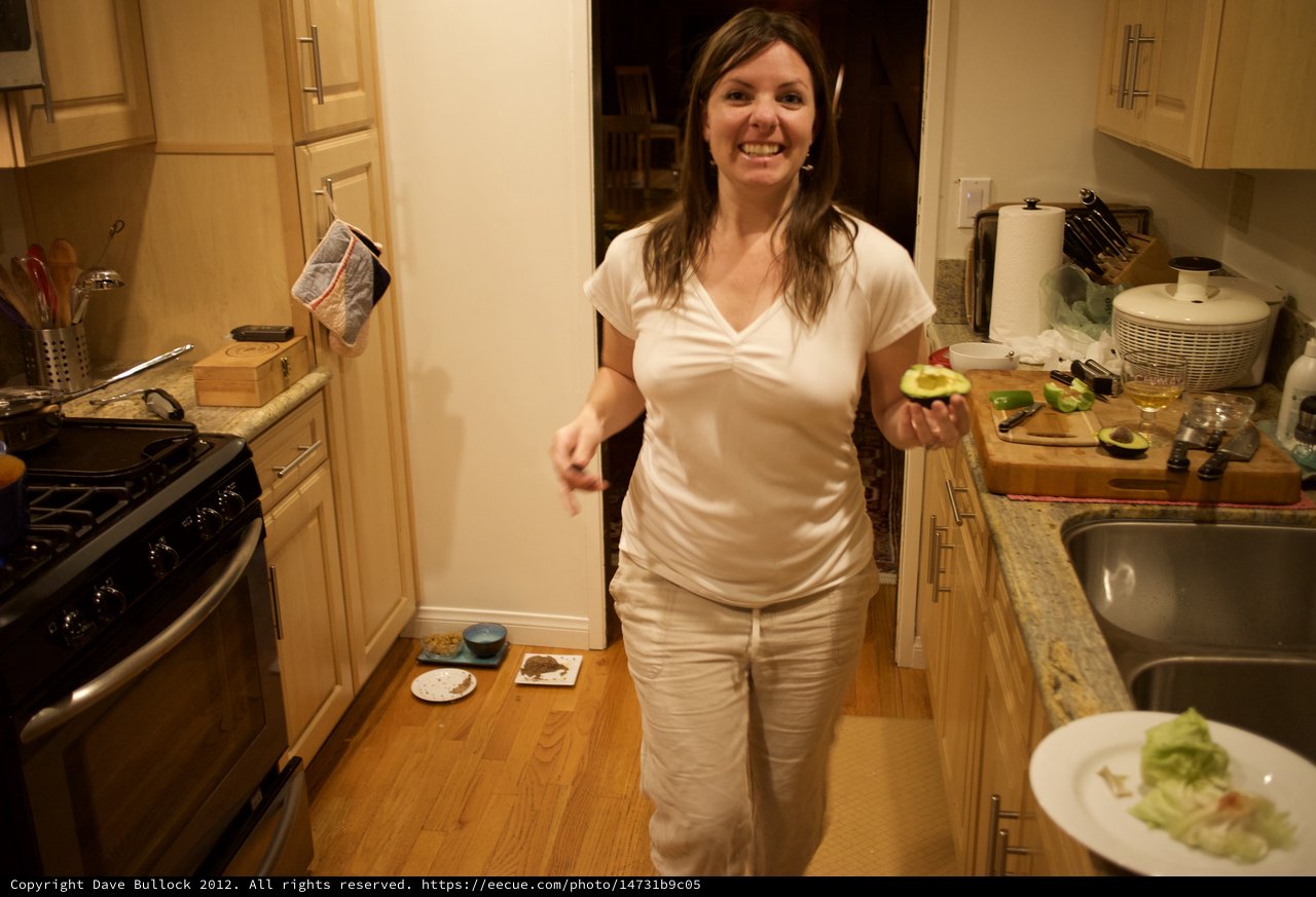 Woman Holding Fresh Avocado in Cozy Kitchen