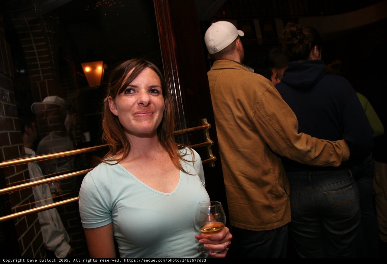 Woman Smiling at Social Gathering in Dimly Lit Bar