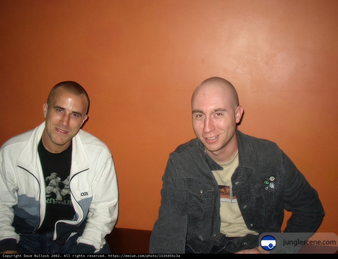 Two Men Sitting in Front of an Orange Wall