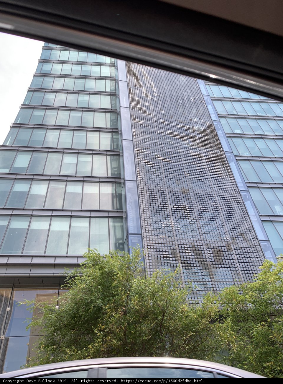 Parked Car in Front of Sky-High Office Building
