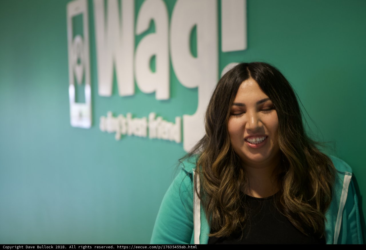 Happy Woman Poses in Front of WAG Logo