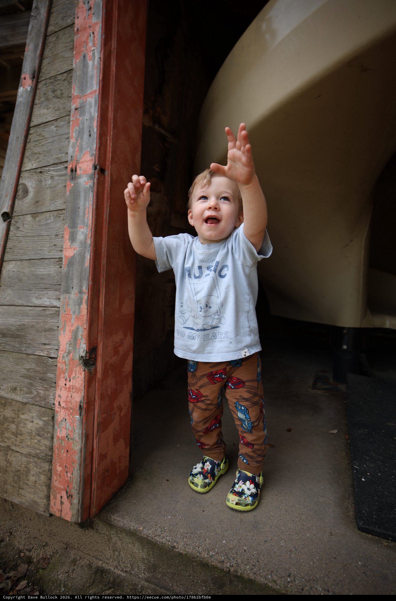 Joyful Toddler Reaching Up in Rustic Doorway