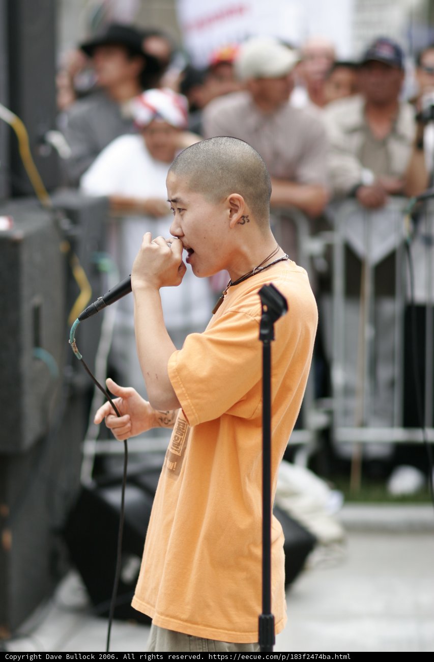 Man with Orange Shirt Speaking into Microphone