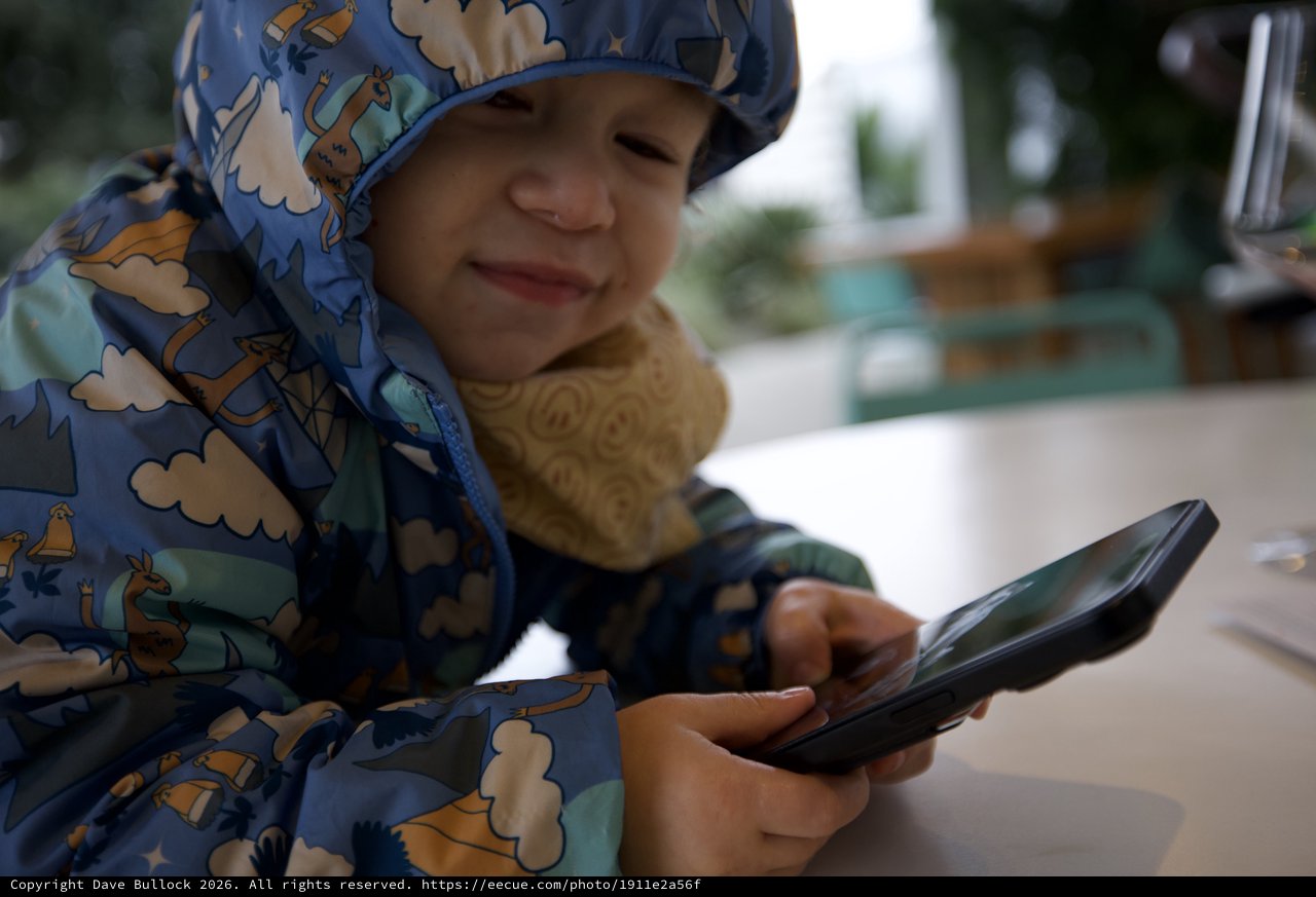 Young Child with Phone at Outdoor Dining Area