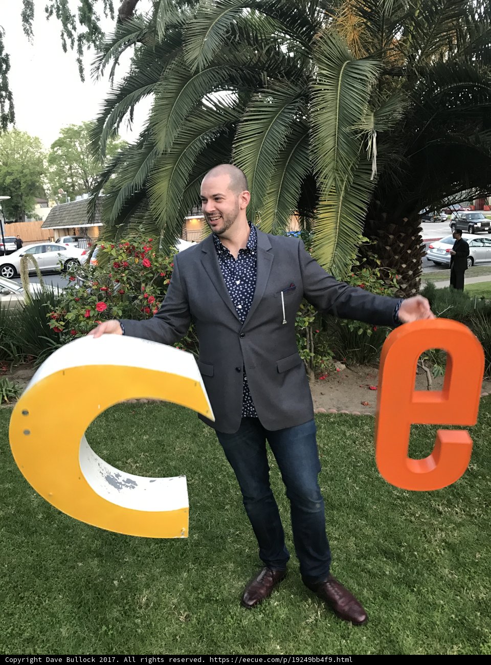 Man Standing Next to Large "C" Sign