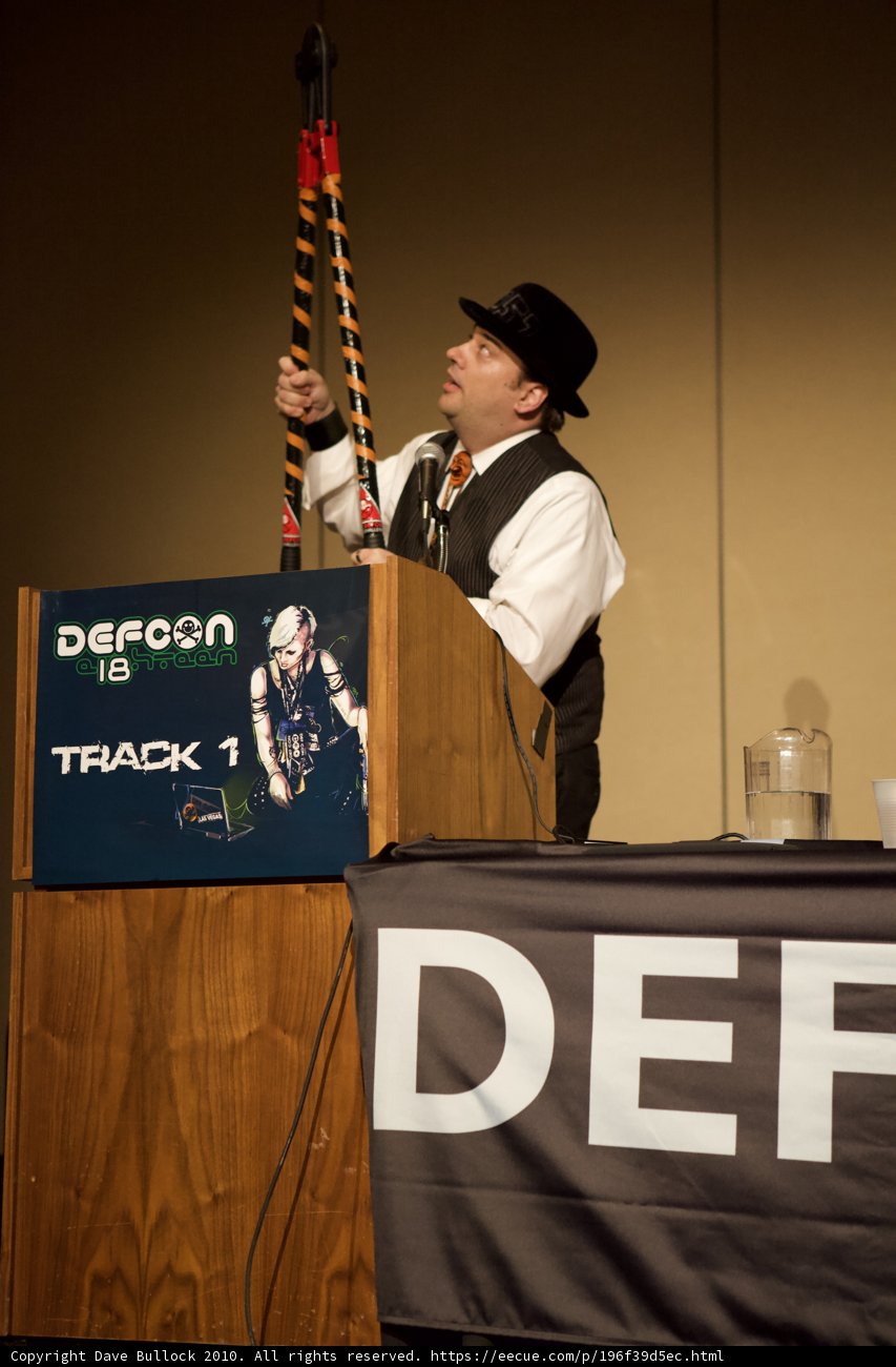 Microphone in Hand Caption: A man holds a microphone while addressing the crowd at Defcon 18.