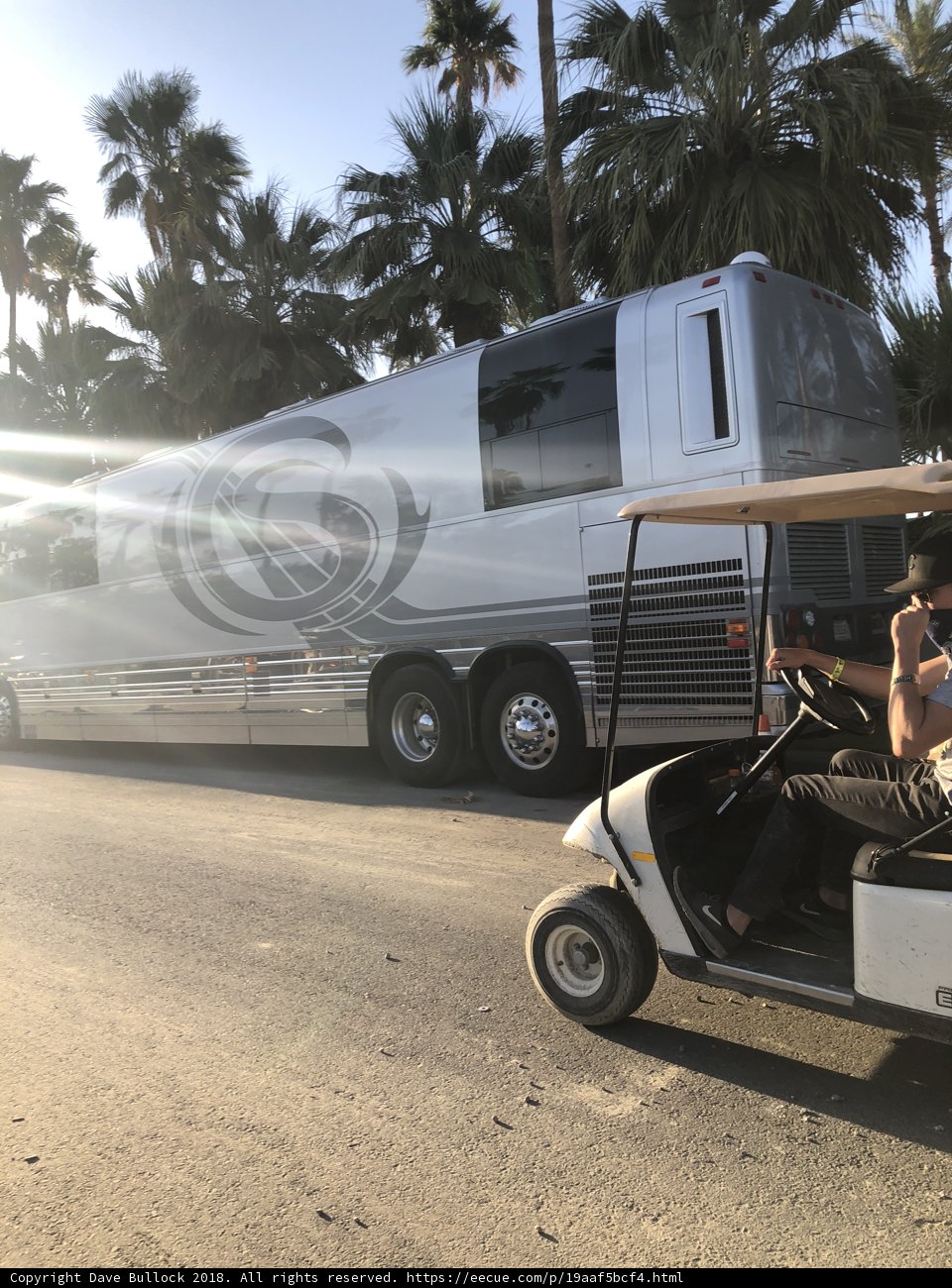 A Man Driving a Golf Cart Alongside a Tour Bus