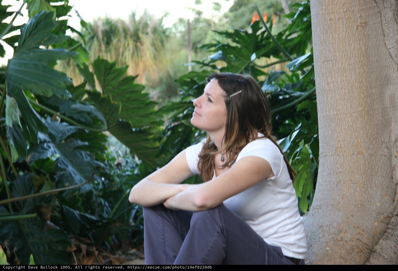 Contemplative Woman Resting Beside Tropical Foliage