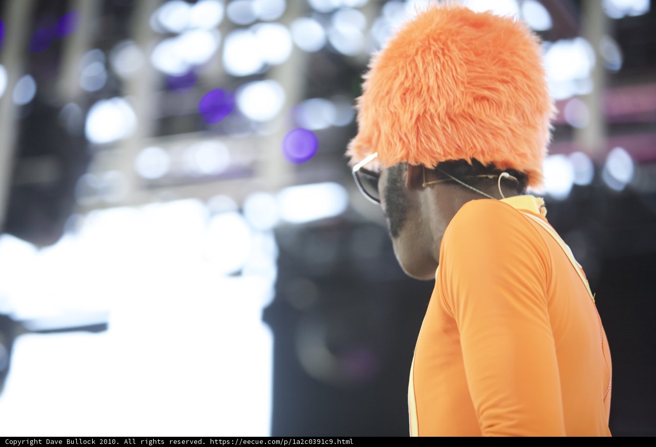 Man in Orange Shirt and Hat Takes the Stage