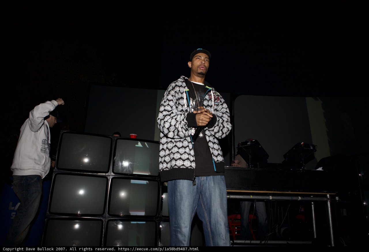Man in Coat Standing in Front of Three Monitors