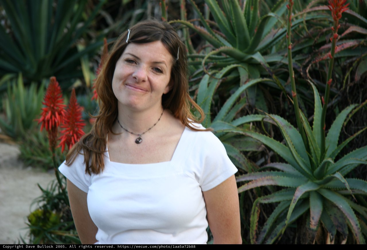Woman Smiling Amid Desert Succulents and Aloe Blooms