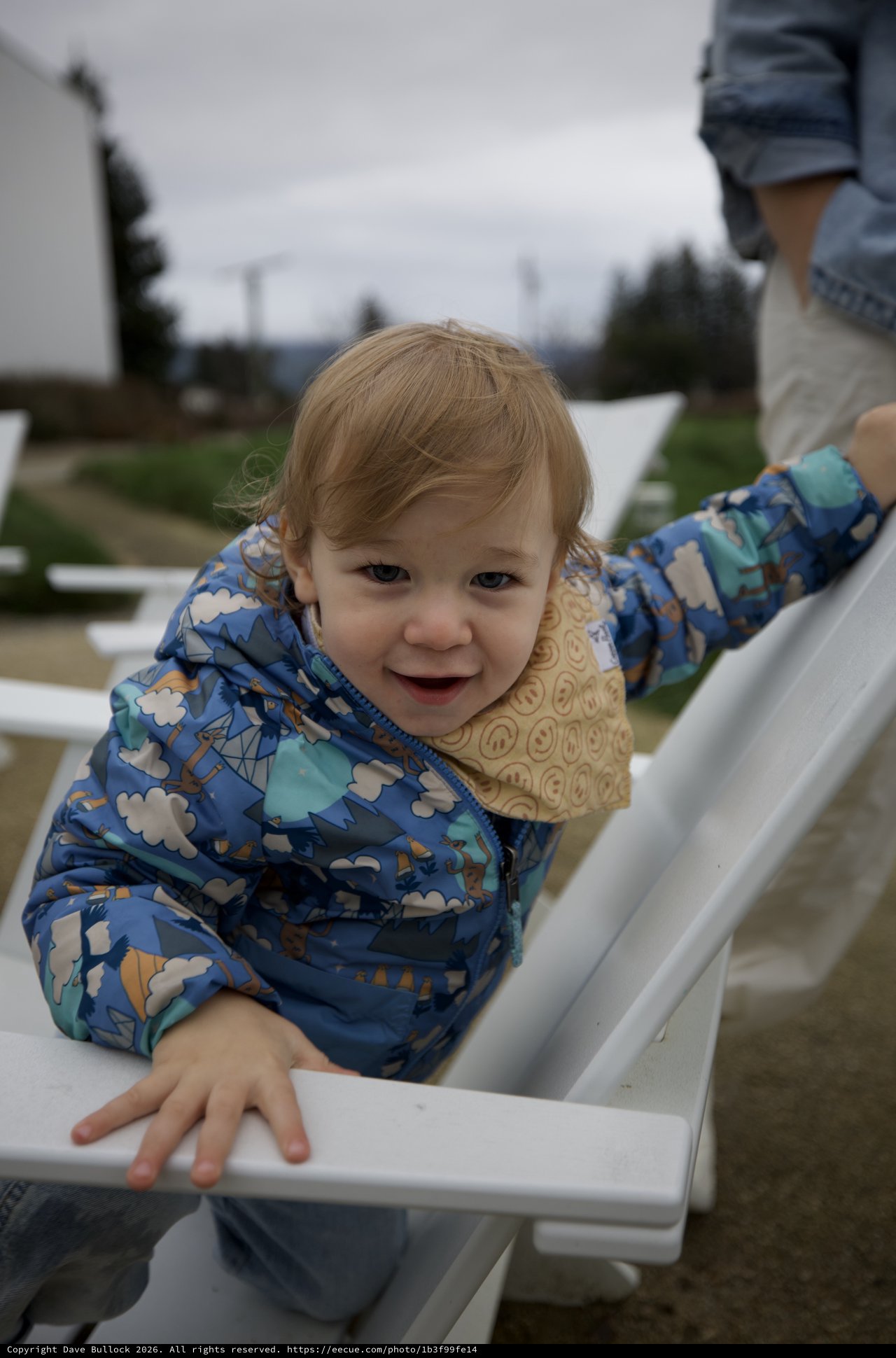 Joyful Toddler Playing on White Fence at Playground