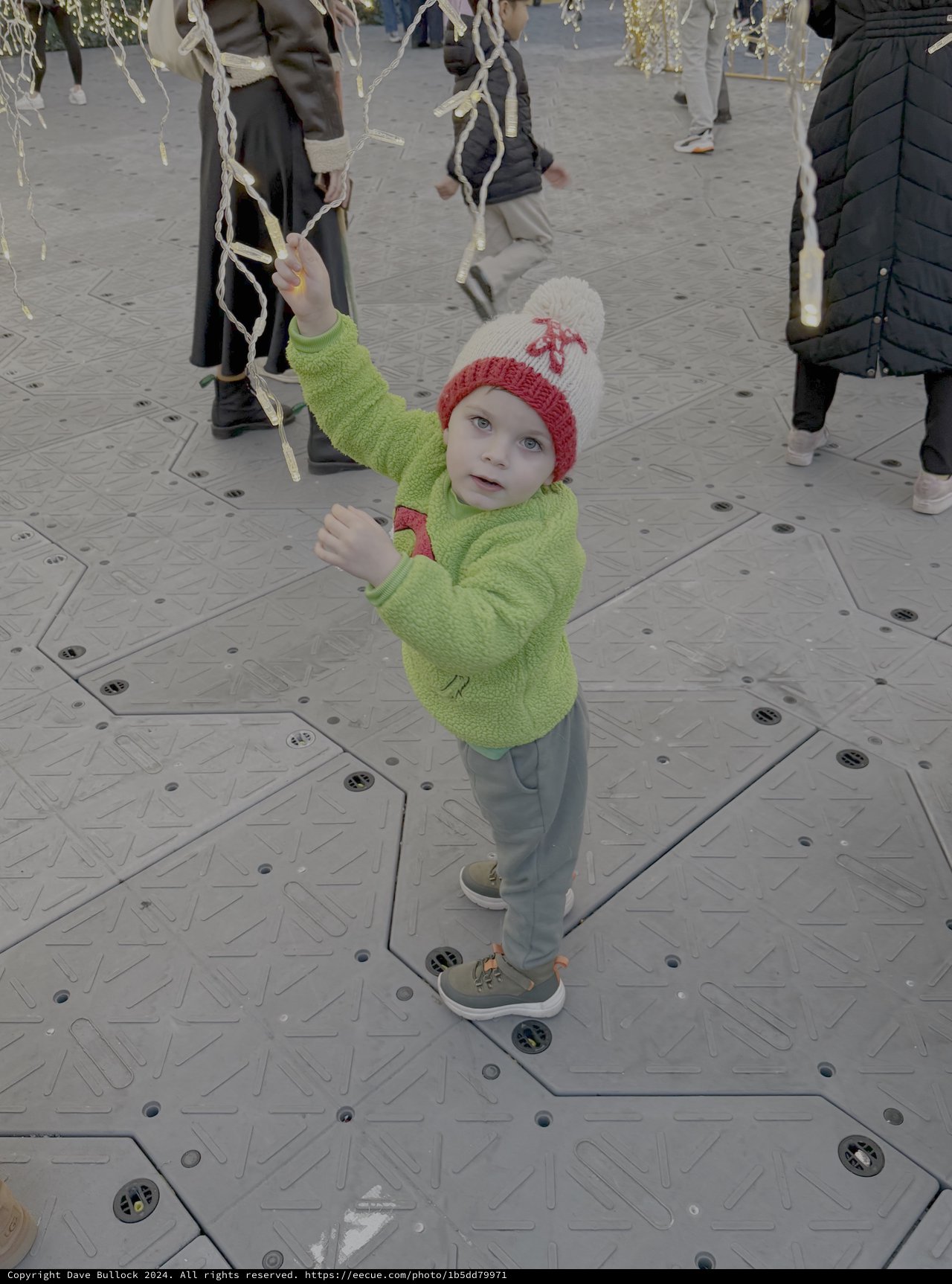 Child Playing with Hanging Ribbons at Winter Market