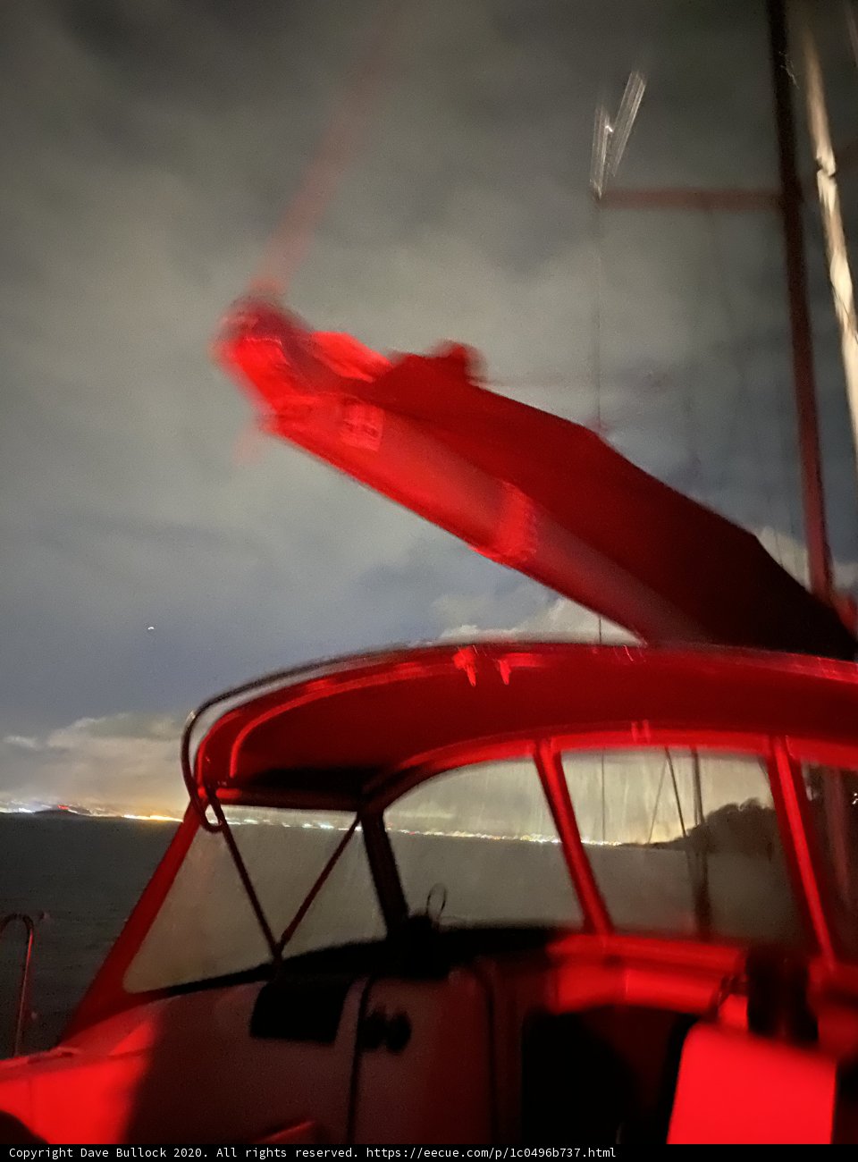Red Light Illuminates Sailboat in the Bay