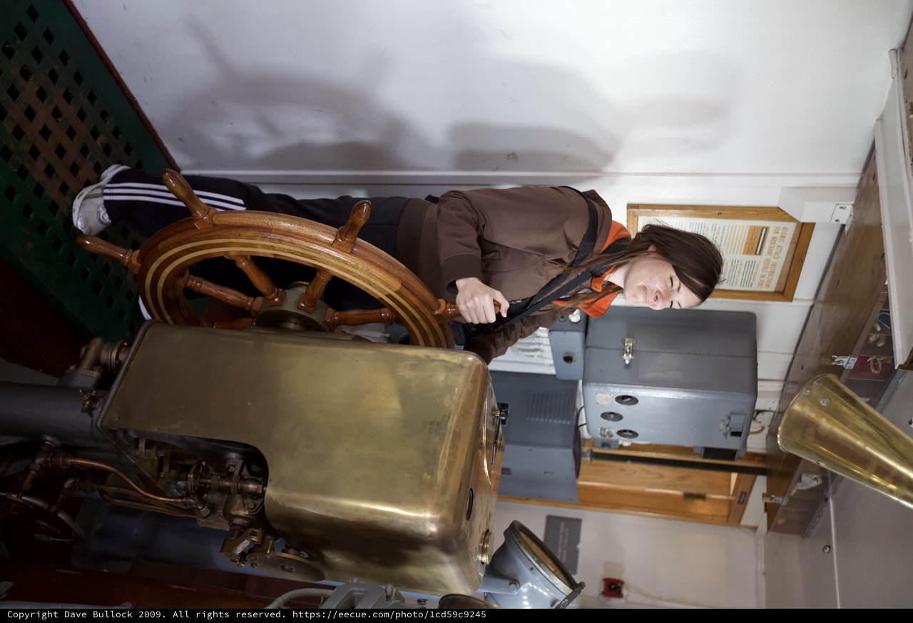 Woman at the Helm of Historic Ship's Wheel