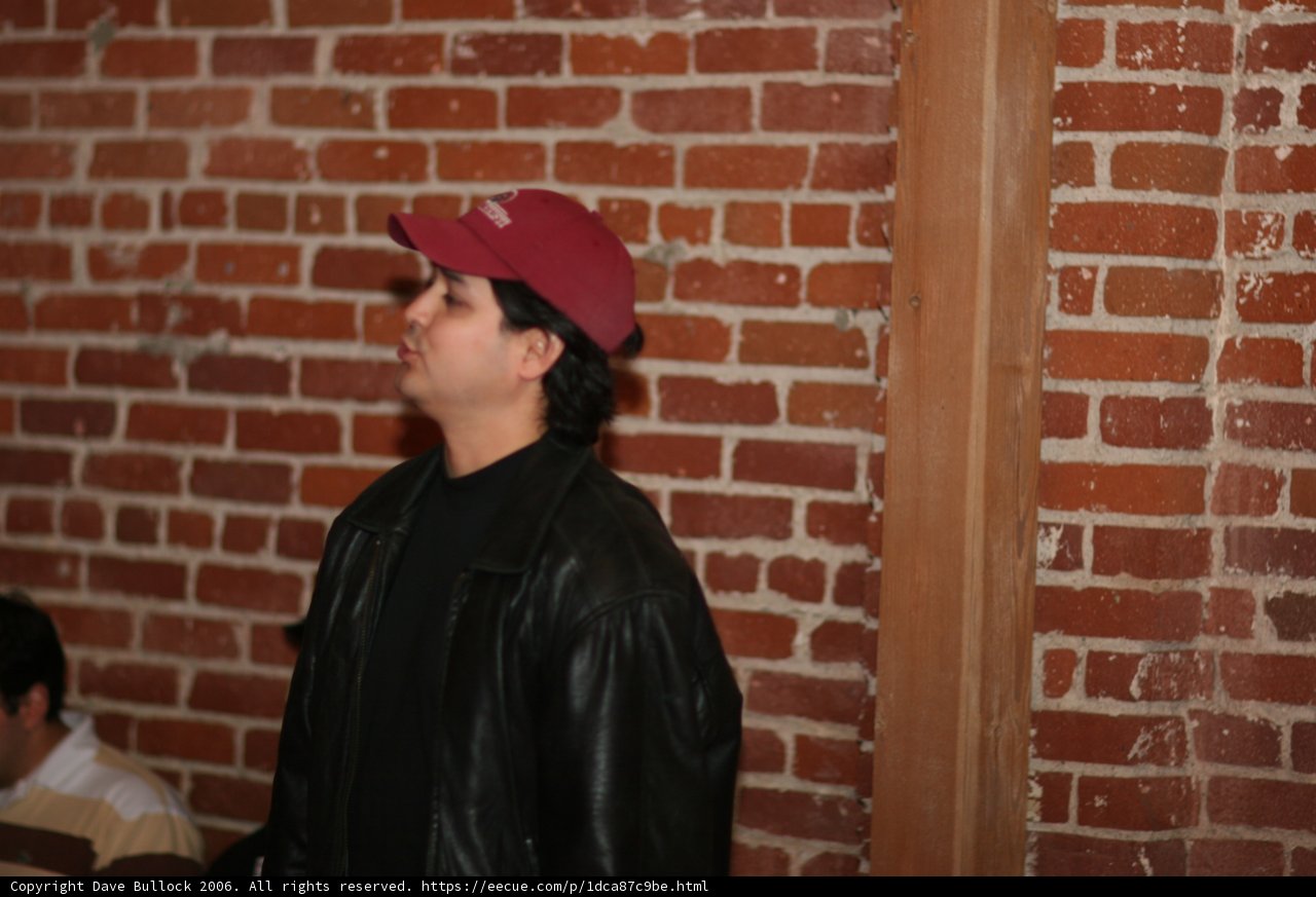 Man in Red Hat Poses next to Brick Wall