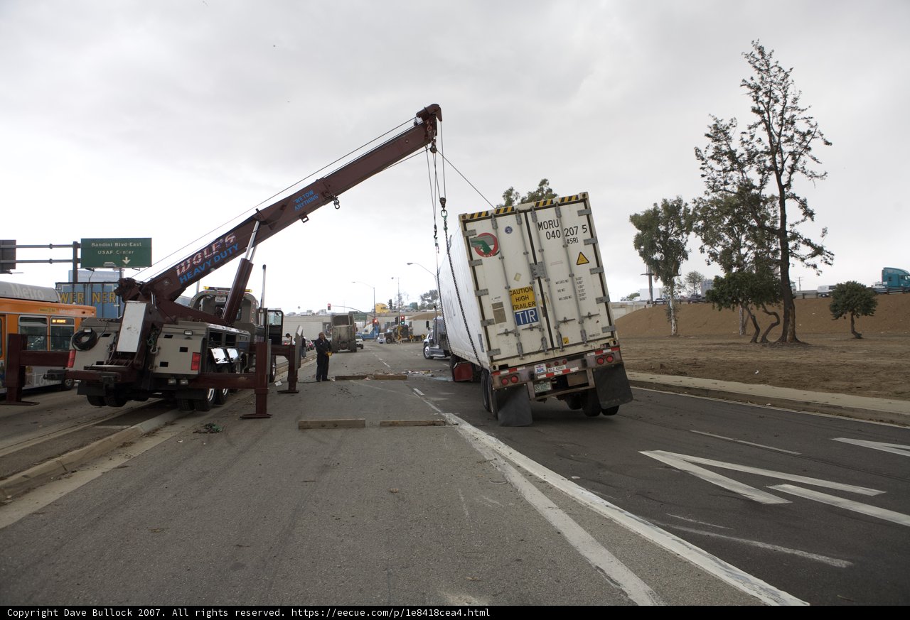 Crane lifting overturned truck on busy city street