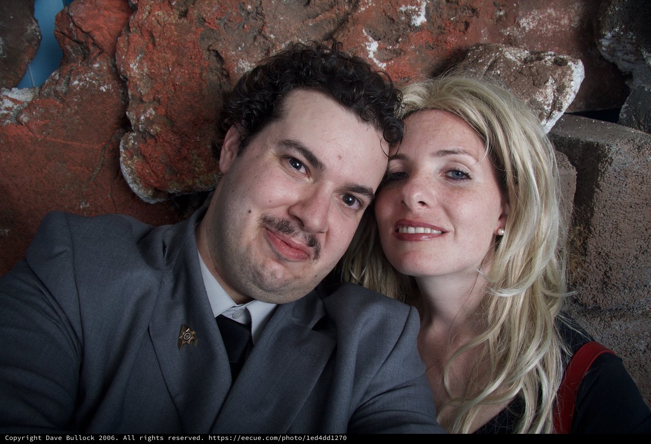 Couple Poses Warmly Against Rustic Brick Wall