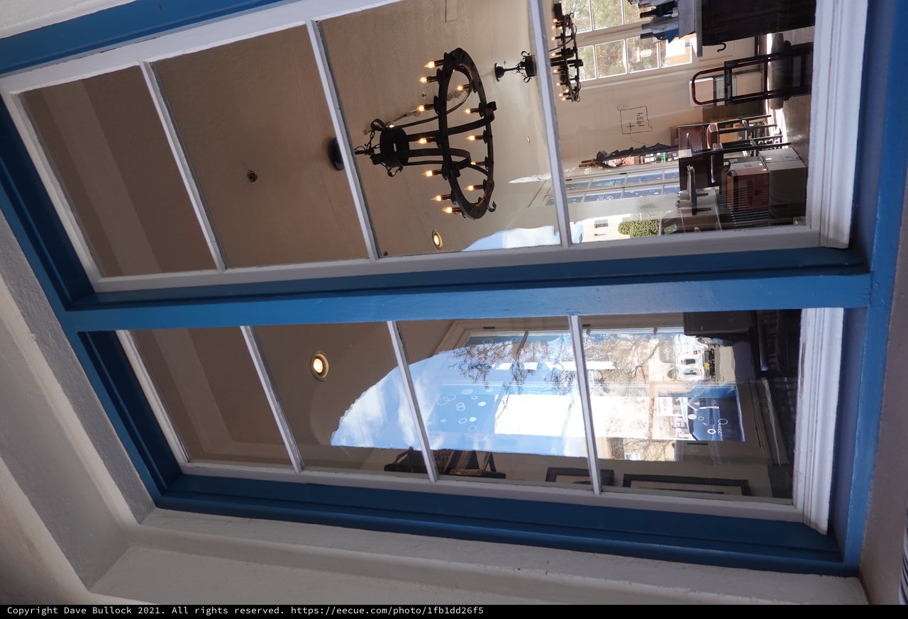 Blue-Framed Window View into Mediterranean Restaurant Interior