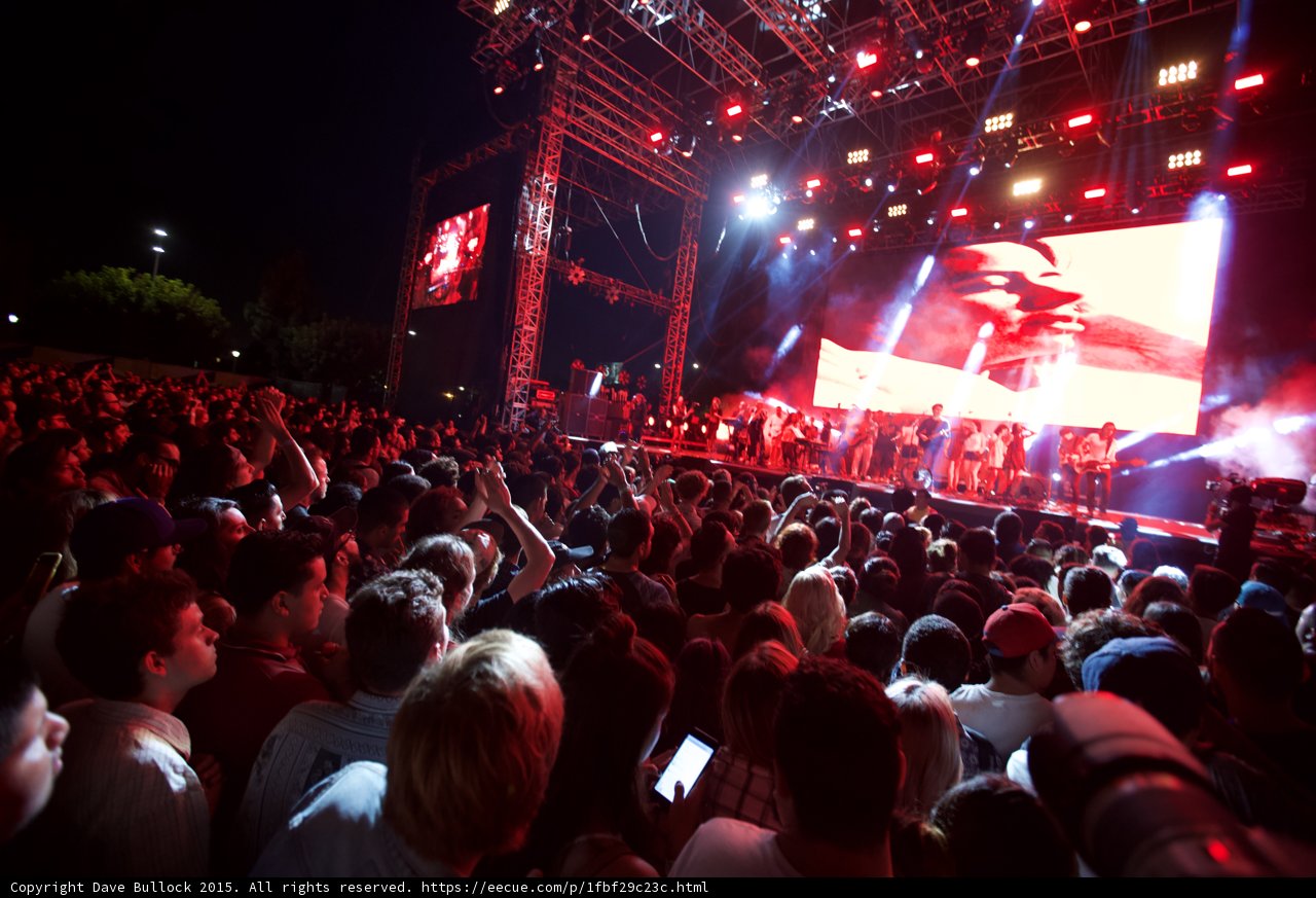 Belle and Sebastian Wide Stage Crowd Arms Raised Phones Video Screen Trees Red Lighting