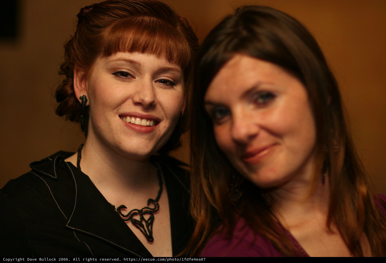 Two Smiling Women at an Indoor Social Gathering