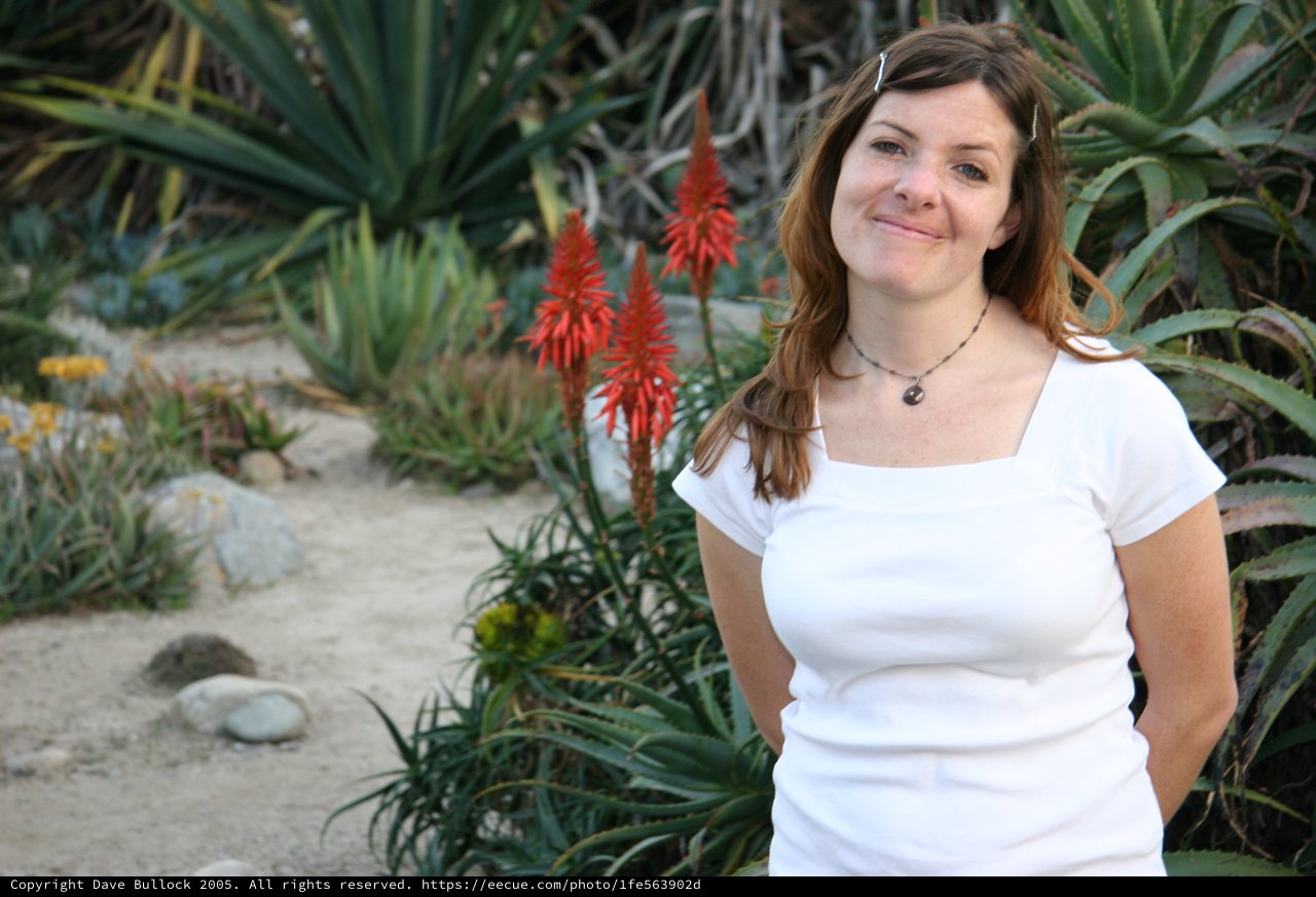 Smiling Woman Among Desert Succulents and Red Blooms