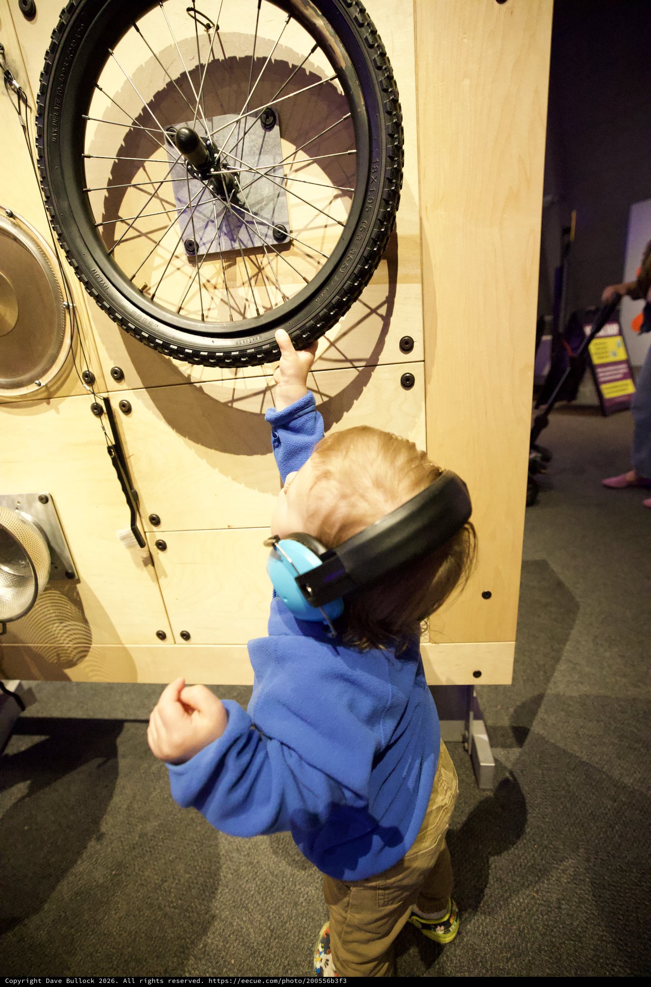Young Child Explores Interactive Bicycle Wheel Exhibit