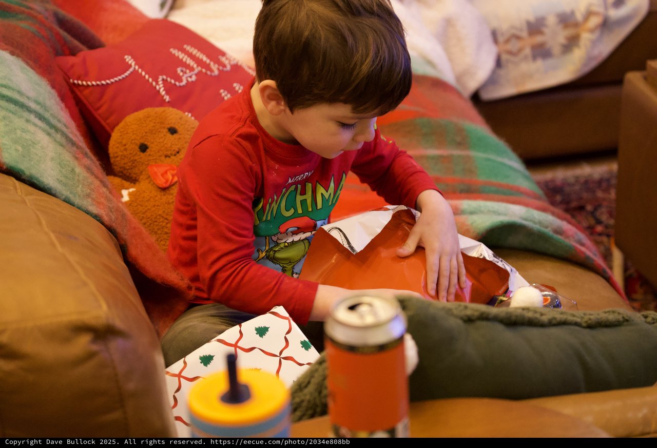 Young Boy Opening Christmas Presents in Cozy Living Room