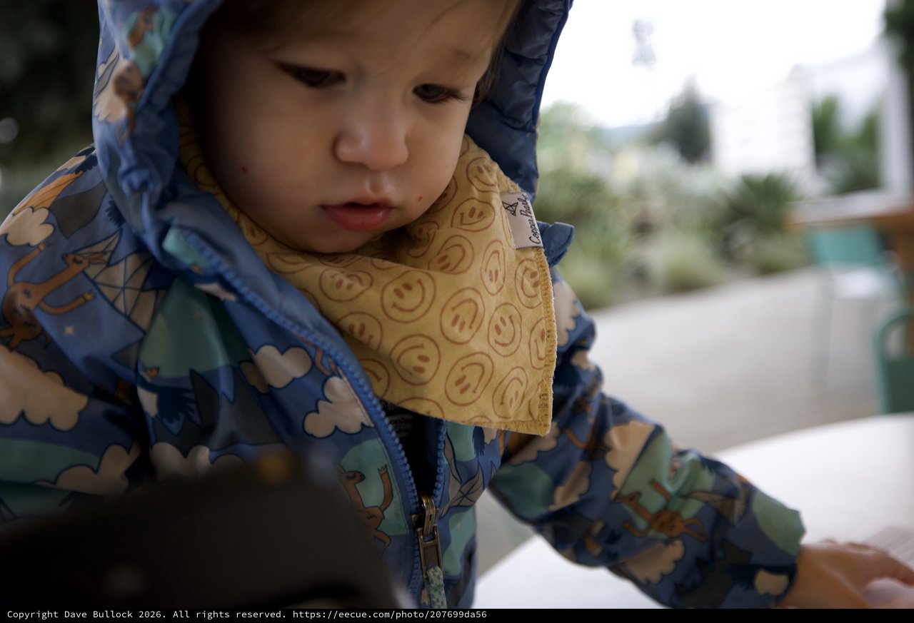 Young Child in Patterned Raincoat with Smiley Bib