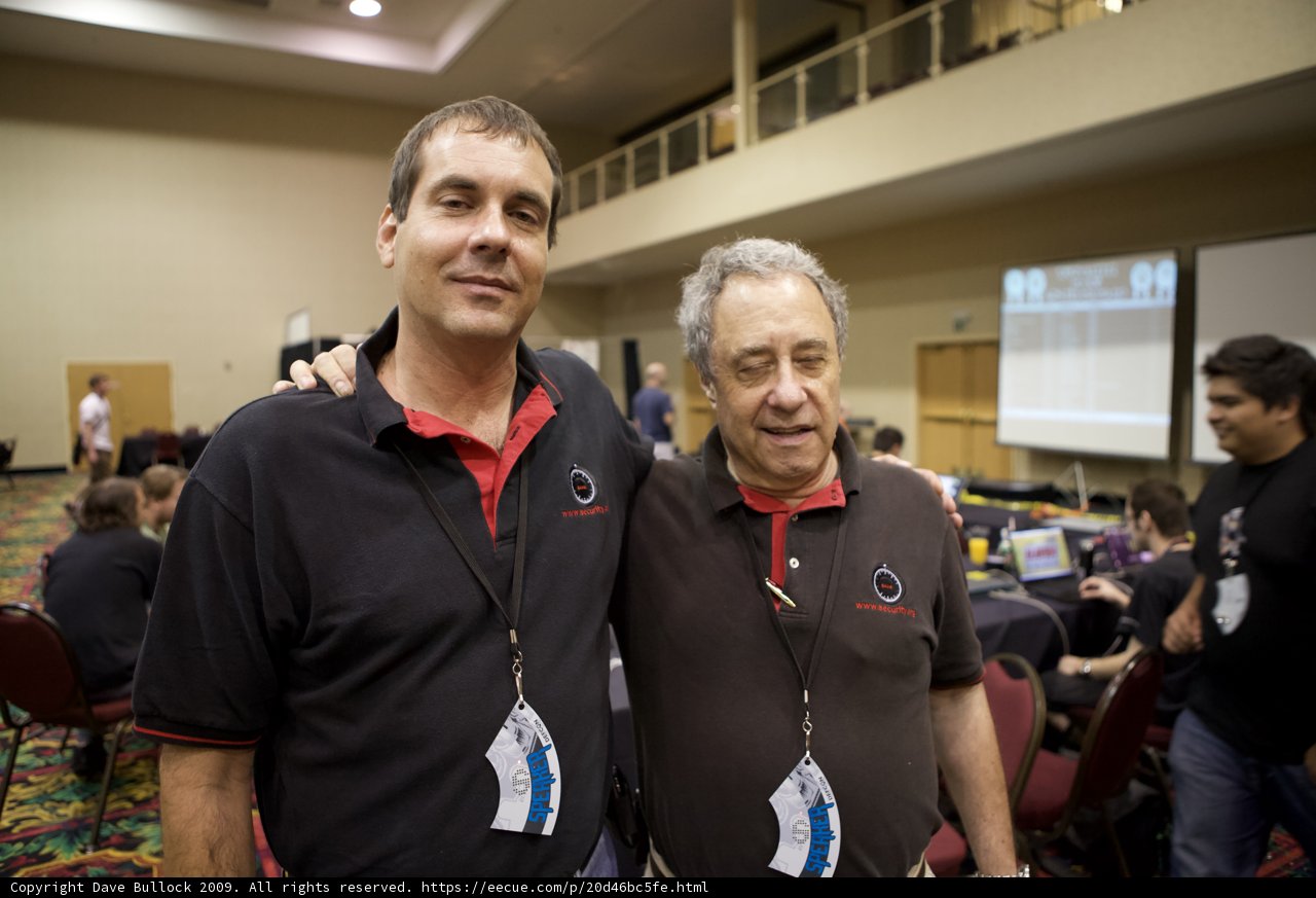 Two Men in Black Shirts Standing Beside Chairs