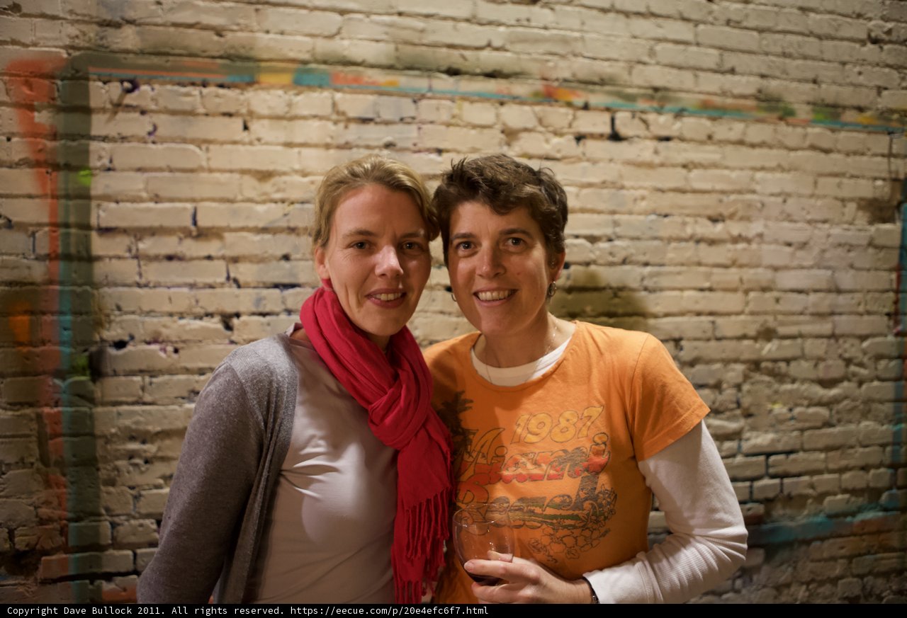 Two Women Posed in Front of Brick Wall