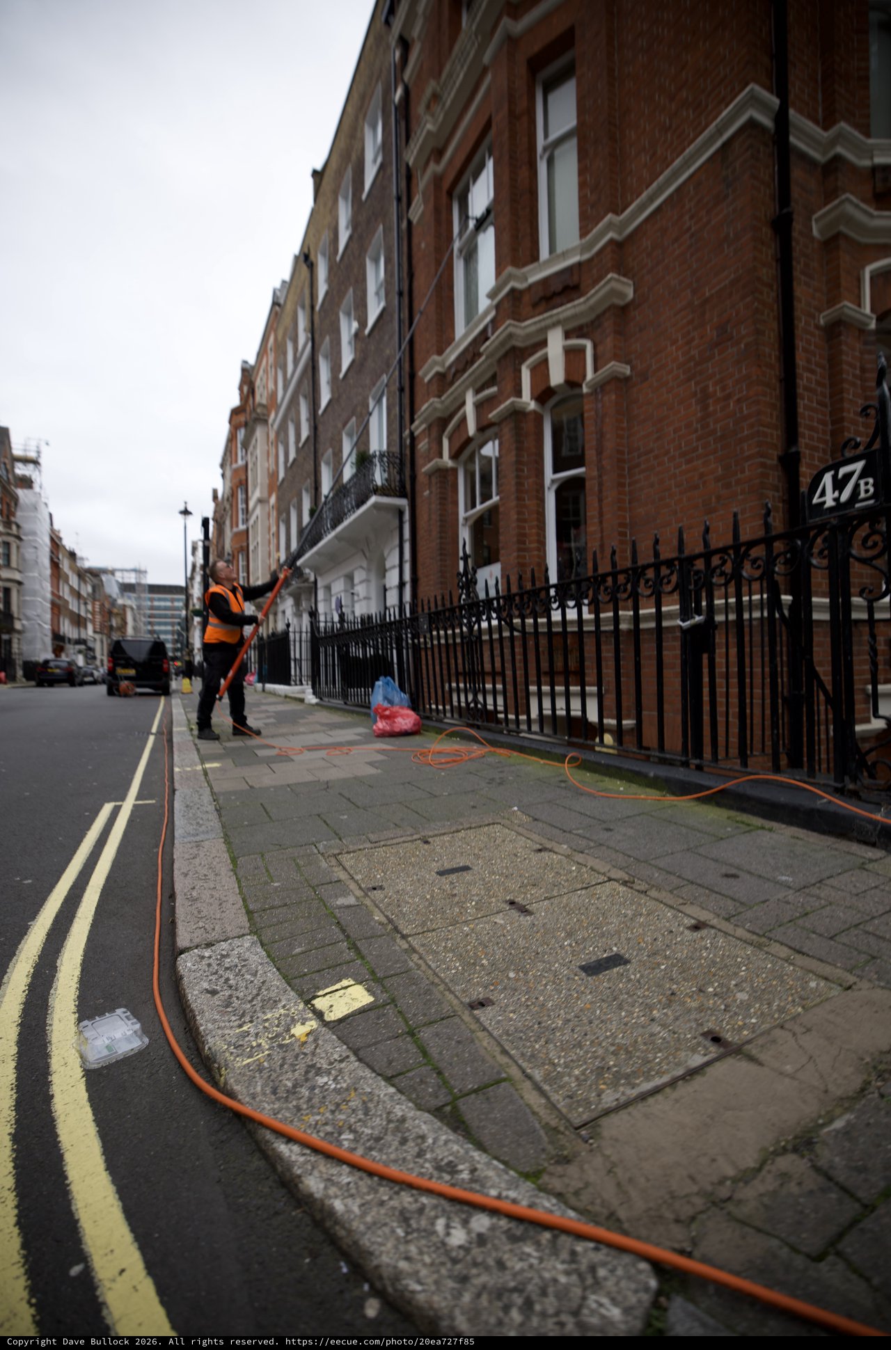 Utility Worker Pressure Washing London Street Sidewalk