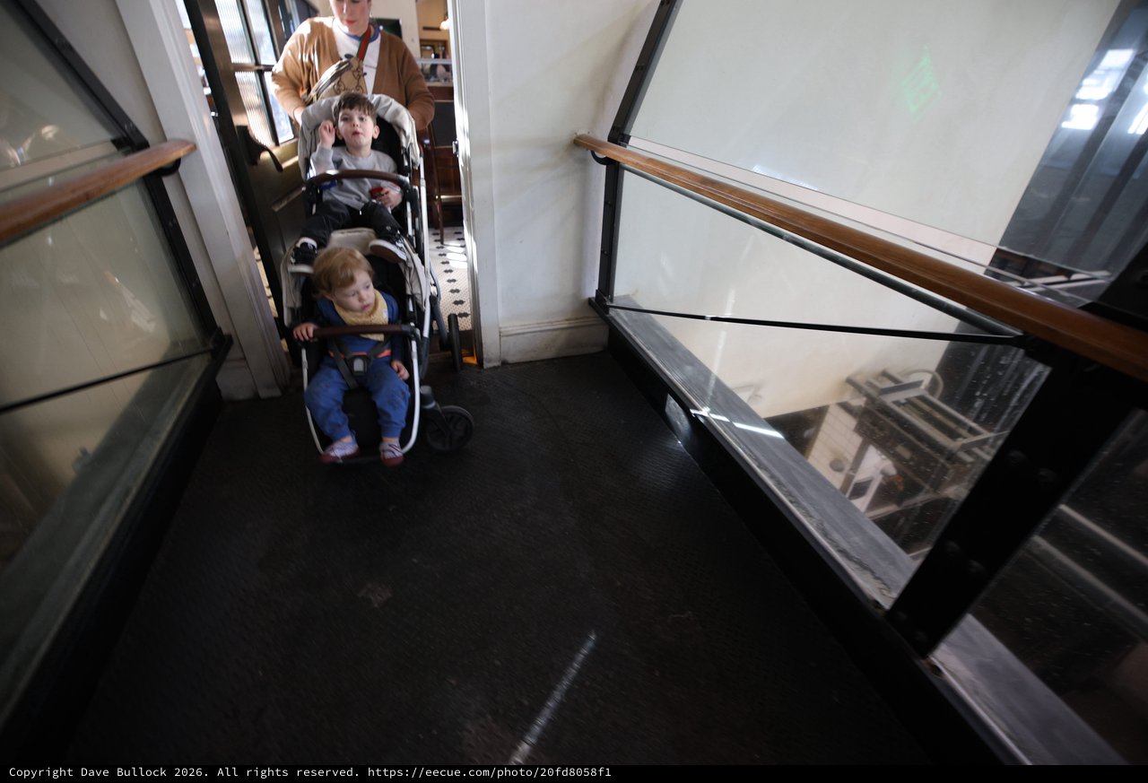 Parent Navigating Double Stroller Through Historic Building Hallway
