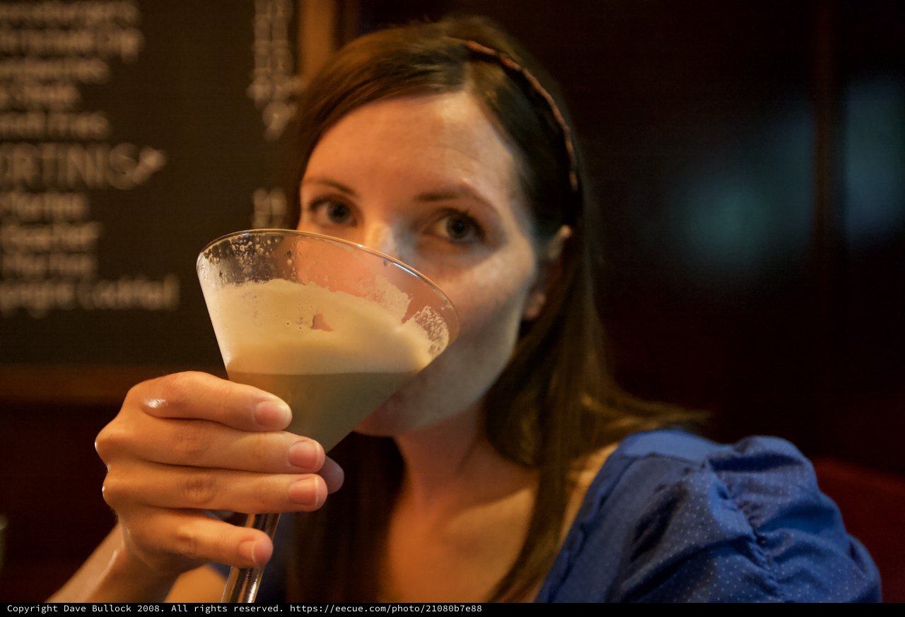 Woman Savoring a Frothy Cocktail at a Bar