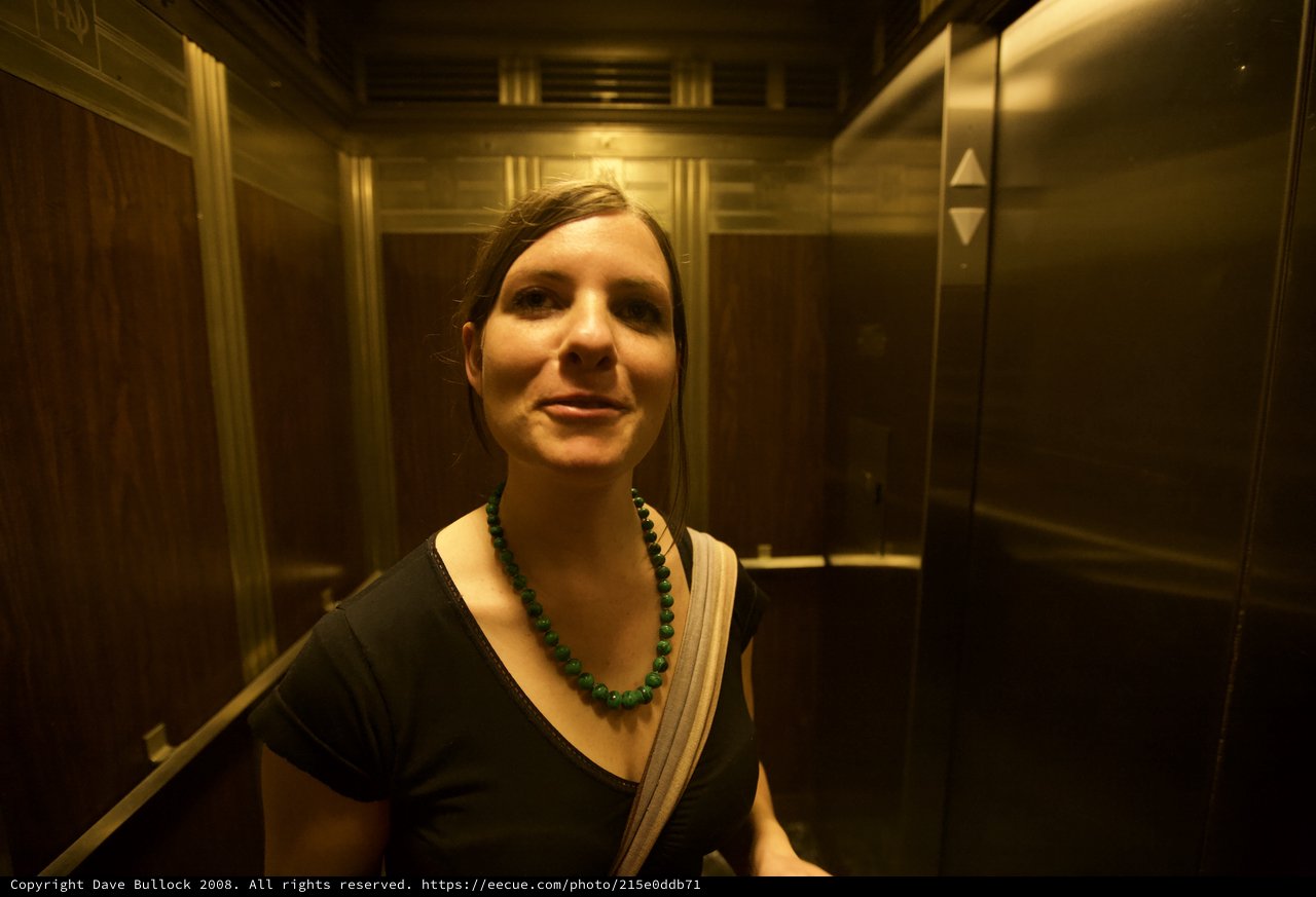 Woman Smiling in Warm-Toned Elevator Interior