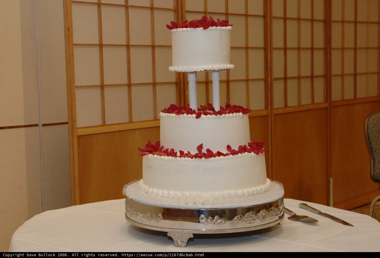 Elegant Three-Tiered Wedding Cake with Red Flowers