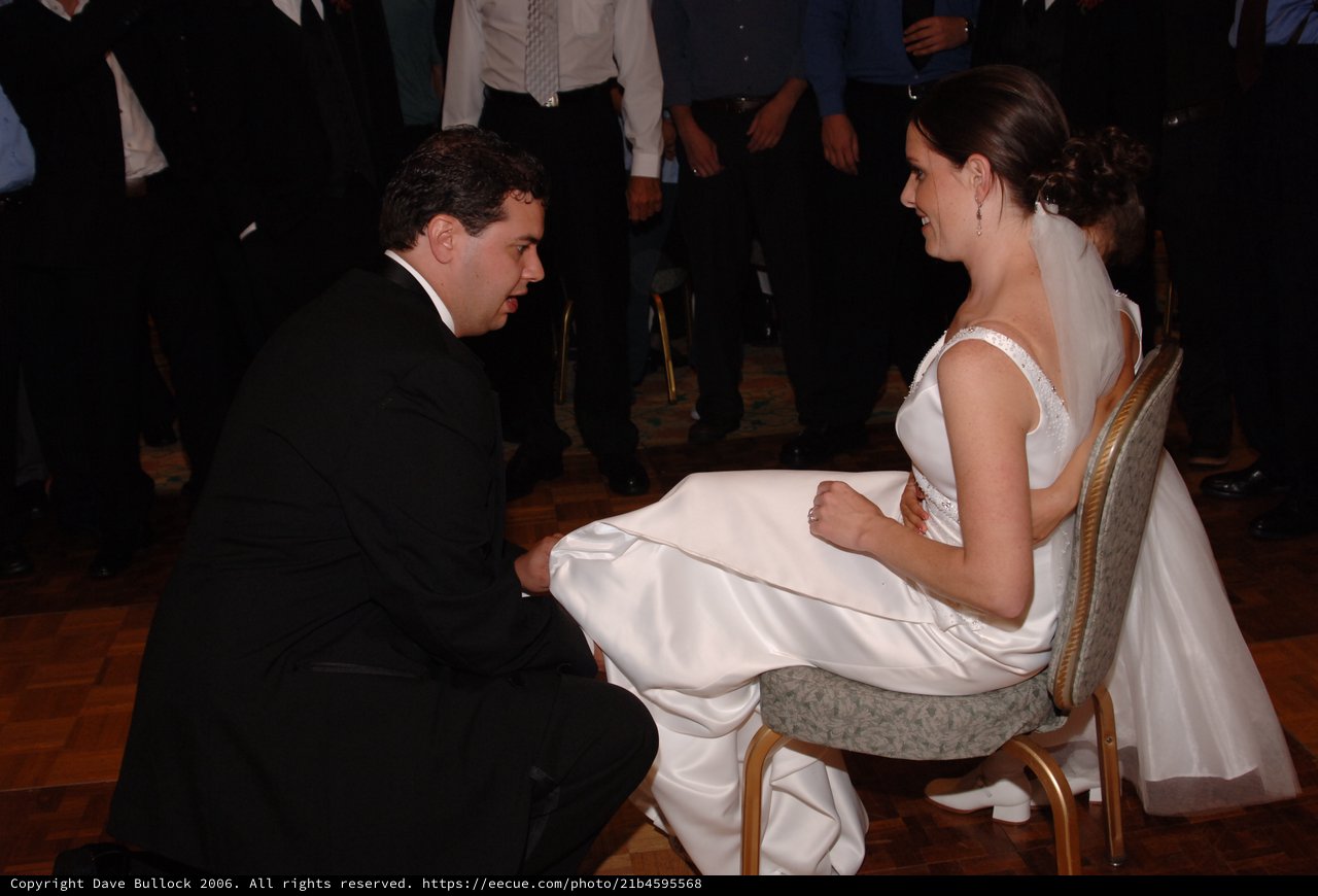 Groom Removes Garter from Smiling Bride at Reception