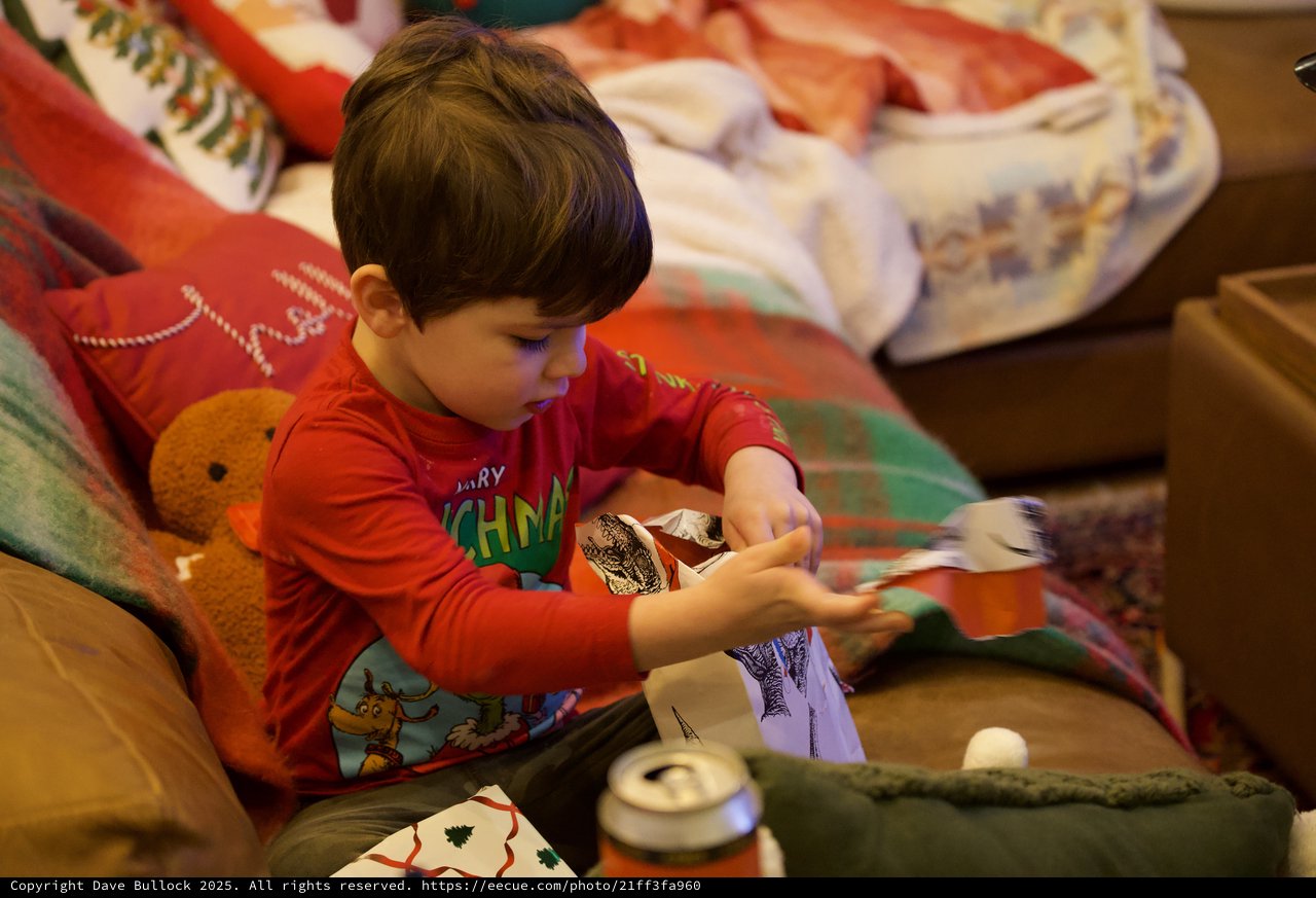 Young Child Opening Christmas Presents on Cozy Couch