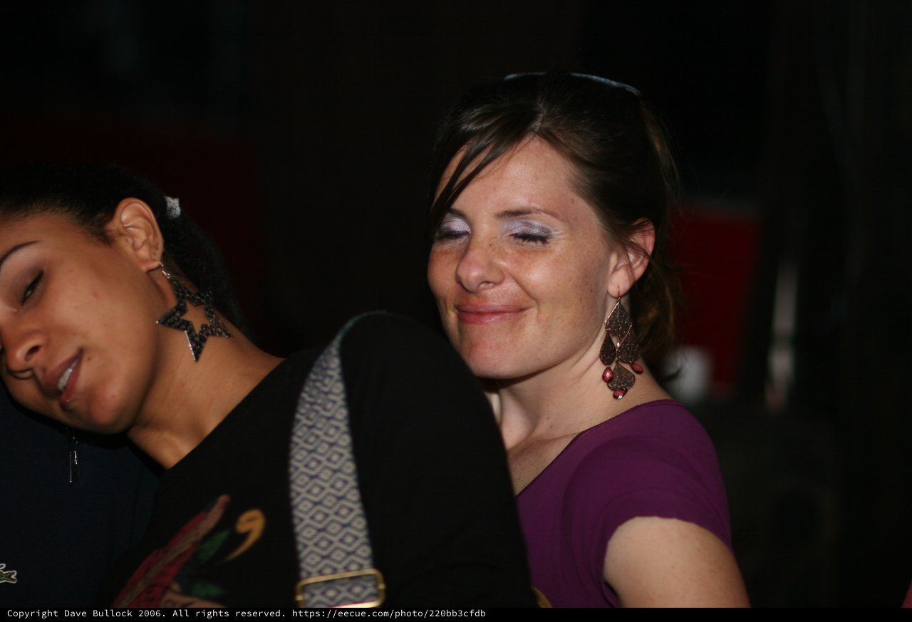 Two Women Smiling at a Nighttime Social Gathering