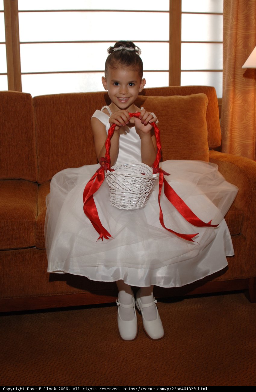 Little girl in a white dress with a basket sitting on a couch