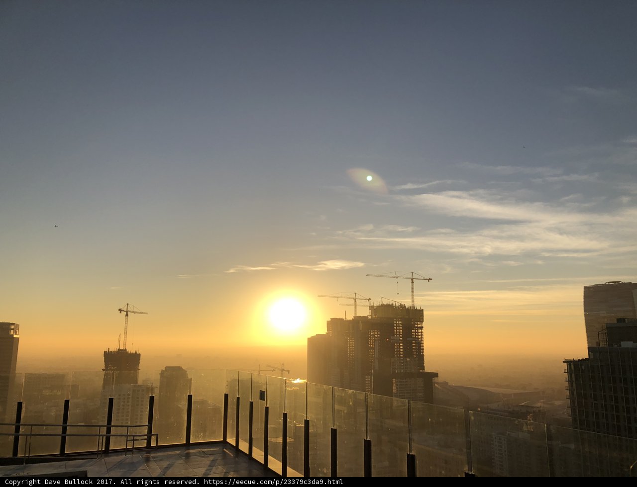 Rising Sun and Cityscape with Construction Cranes