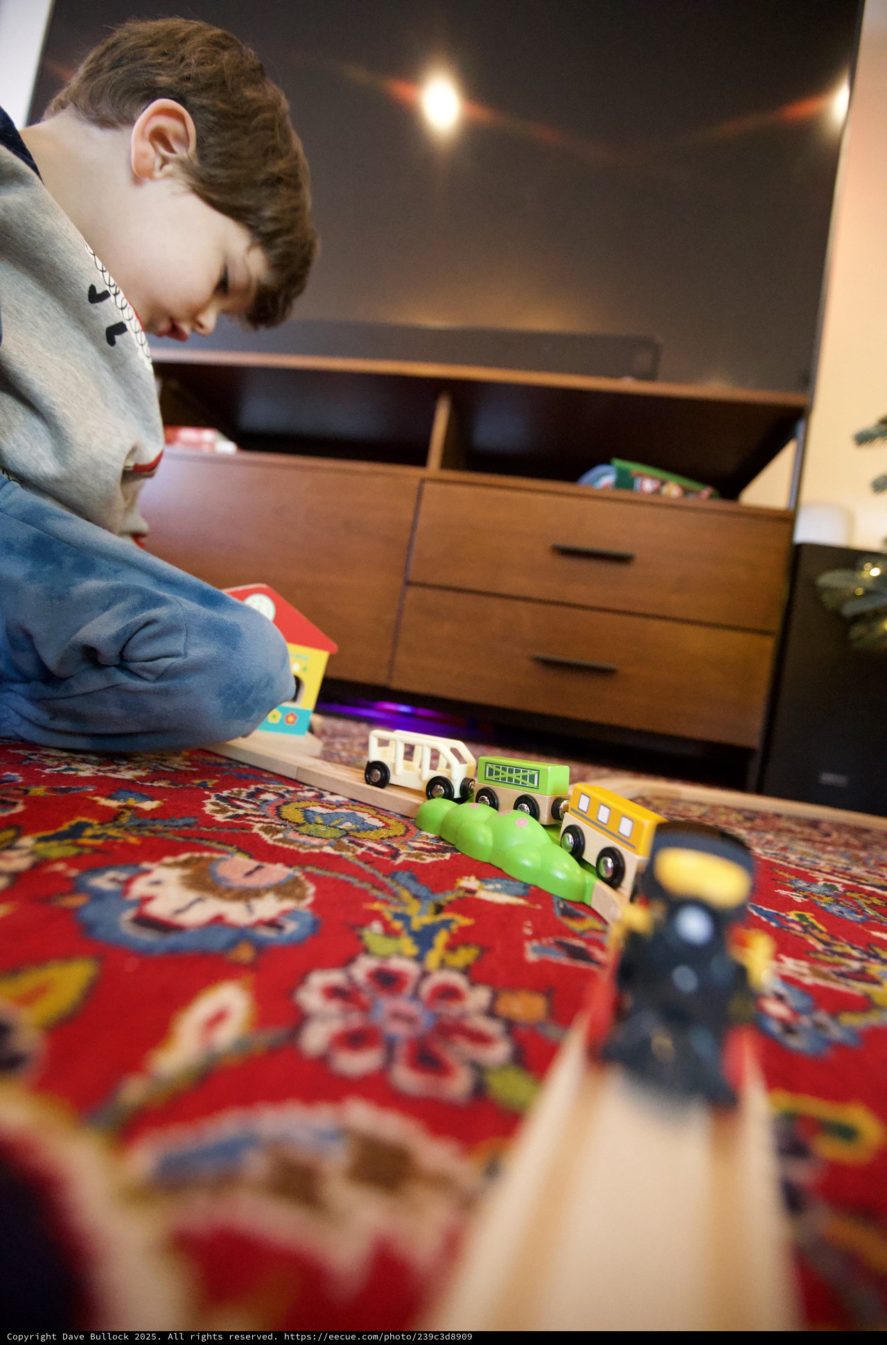 Child Playing with Wooden Train Set on Ornate Rug