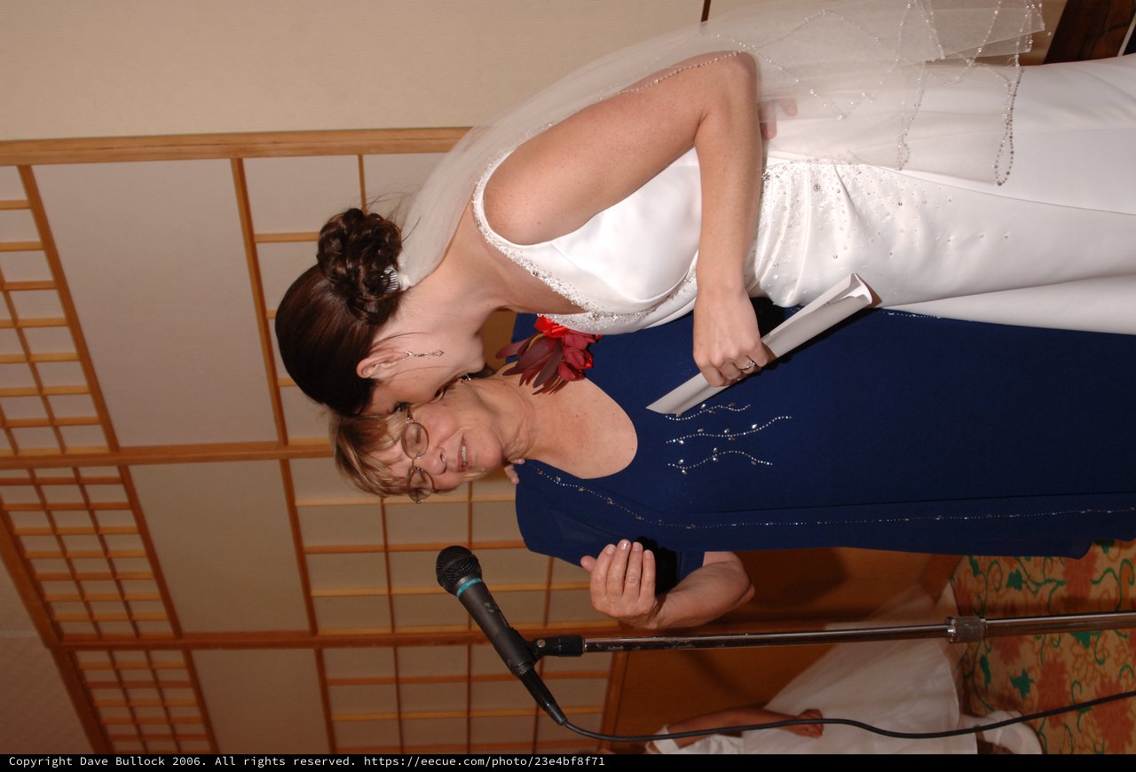 Bride and Elder Woman Share Tender Moment at Microphone