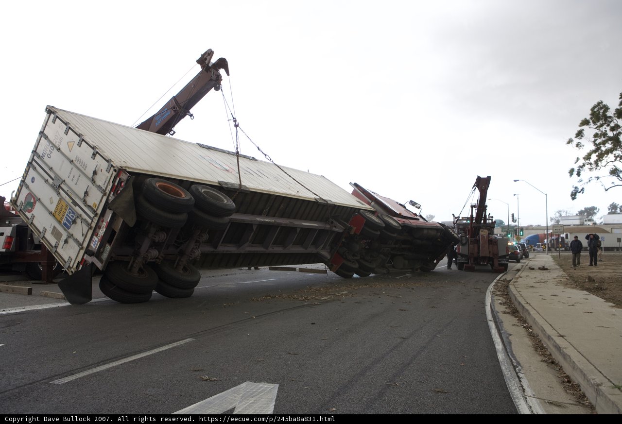 Crane lifting an overturned truck off the road