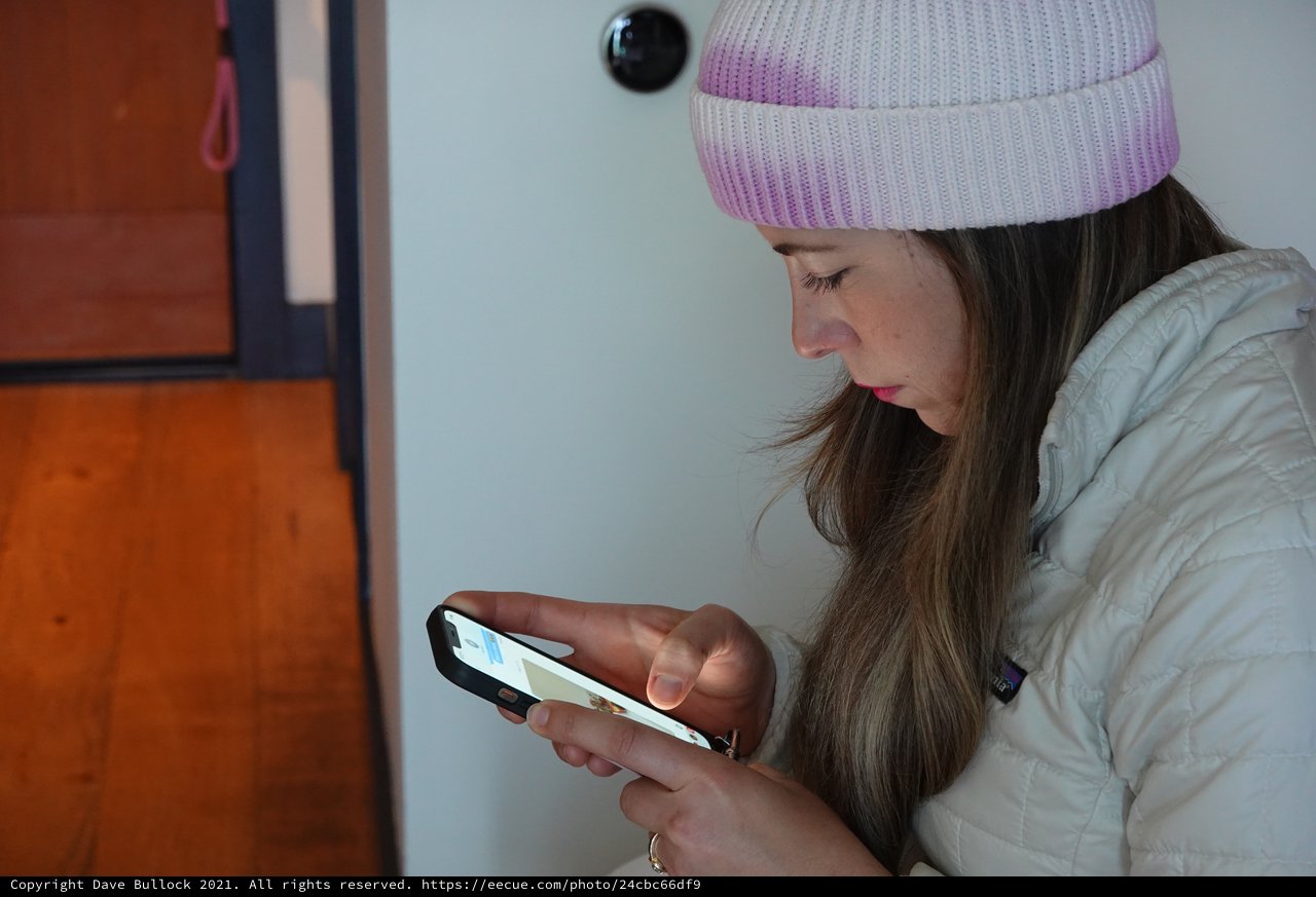 Young Woman Using Smartphone in White Puffy Jacket