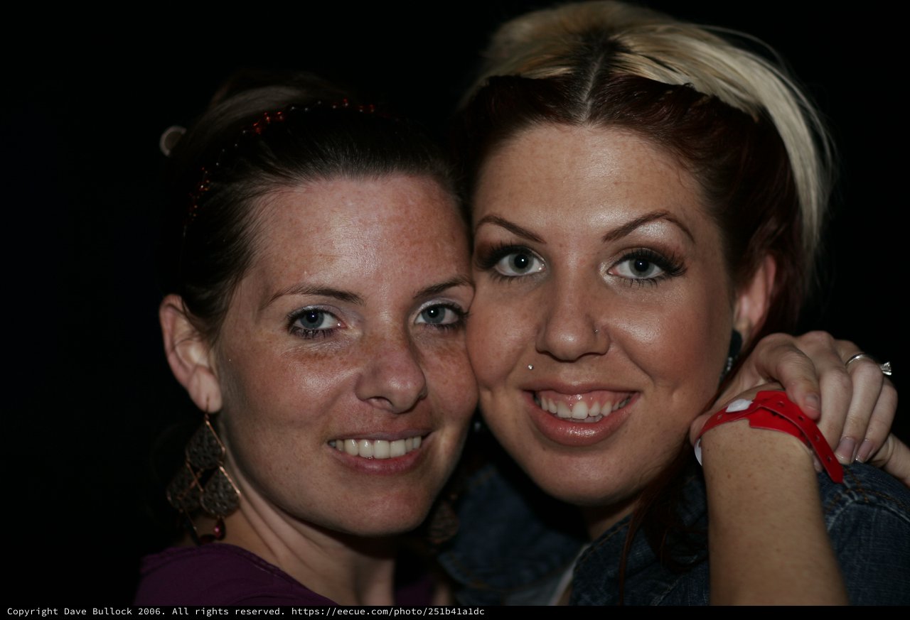 Two Friends Smiling Together at Nighttime Event